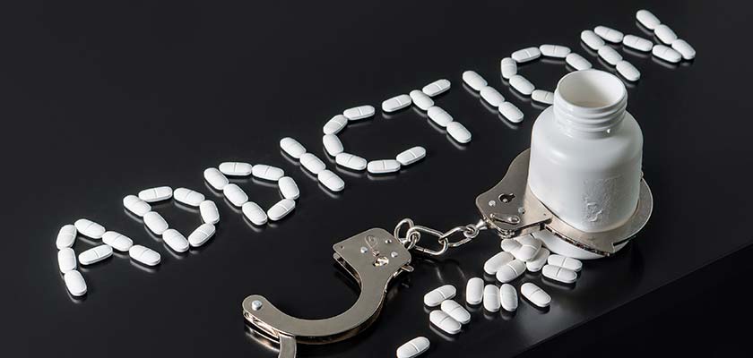 таблетки и наручники на столе - концепция зависимости
