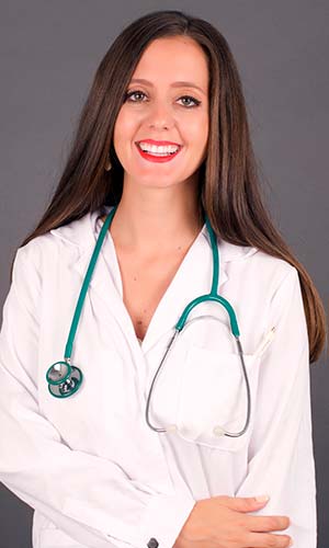женщина врач в белом халате улыбается и смотрит в камеру
